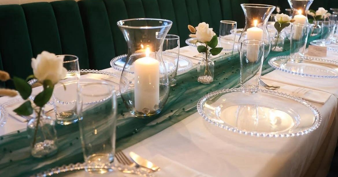 Festlich gedeckte Tafel mit grünem Läufer und Kerzen